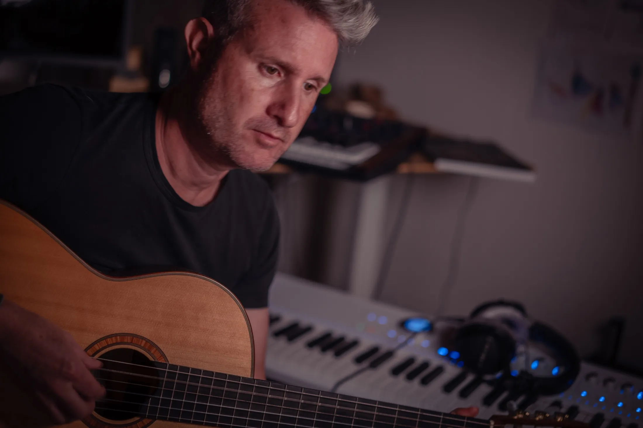 Stefan Ruf playing guitar between analogue instruments and digital studio equipment